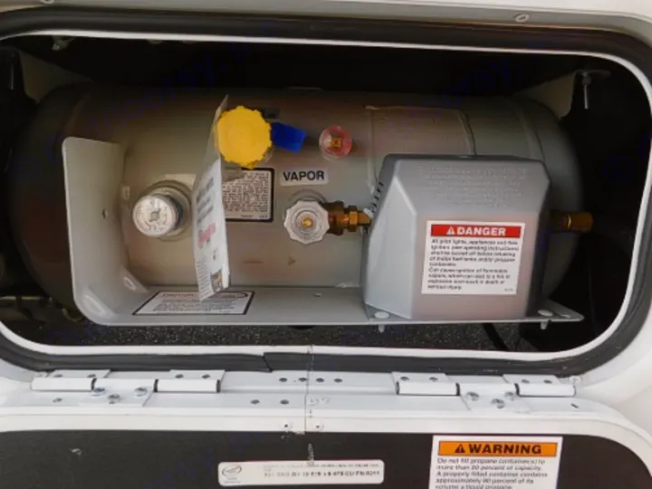 RV rental: Close-up of an RV propane gas tank with its gauge, valves, and safety labels. Visible "VAPOR" text.. Entegra Coach Odyssey 2019