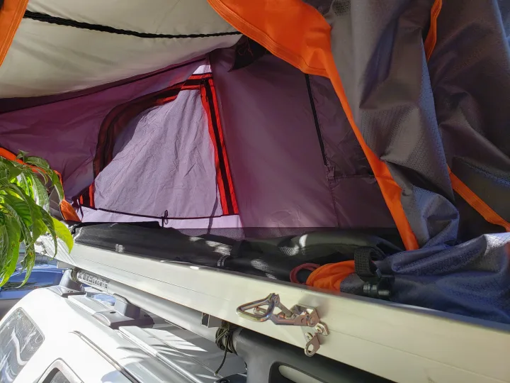 Inside a vibrant orange and purple rooftop tent on an RV rental vehicle, perfect for outdoor adventure.. NISSAN XTERRA 2014