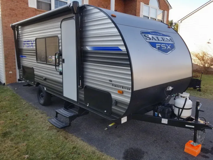 Flush passenger side view of the camper, tow approved. Offers large dinette window, retractable stairs, two under cabin storages and propane tank.. Forest River Salem FSX 2021
