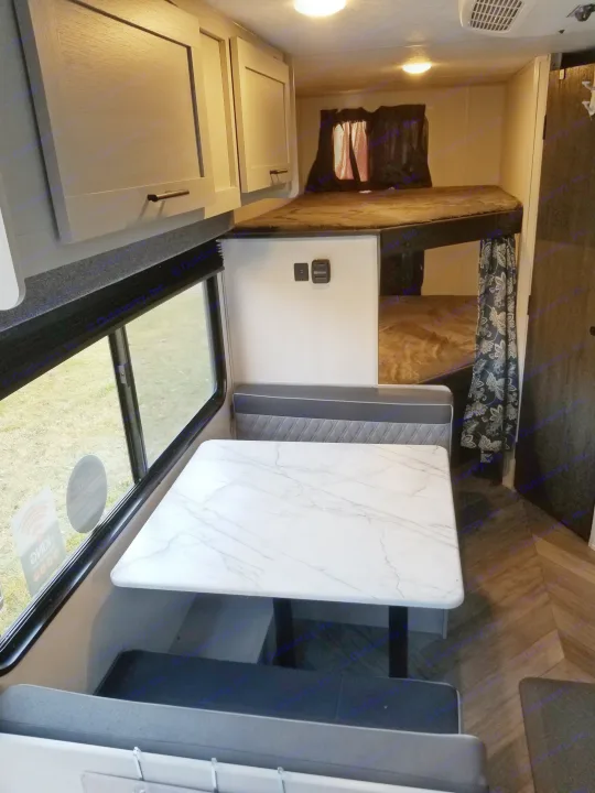 Family size dining table fitting for family meals and the view of your journey. Included view of full sized bunk bed in the rear.. Forest River Salem FSX 2021