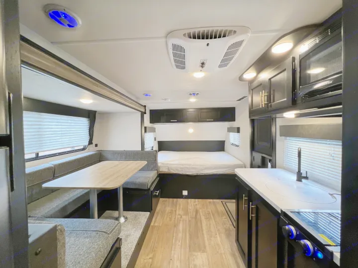 Modern RV rental interior: kitchen, dinette, and bed area. Brightly lit and spacious.. Forest River Cherokee Wolf Pup 2022