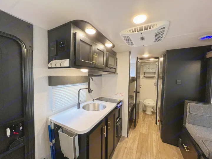 Inside this modern RV rental: a well-appointed kitchen, overhead AC unit, and compact bathroom. Perfect for road trips!. Forest River Cherokee Wolf Pup 2022