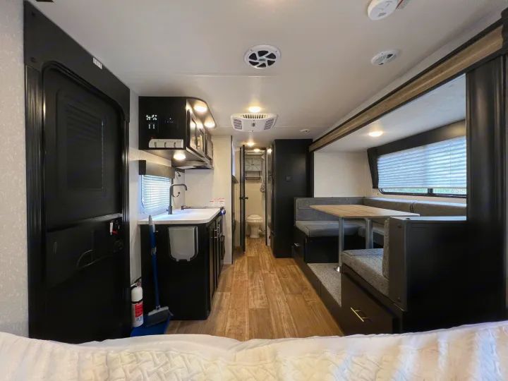 Spacious RV rental interior with a fully equipped kitchen, comfortable dining booth, and bedroom area.. Forest River Cherokee Wolf Pup 2022