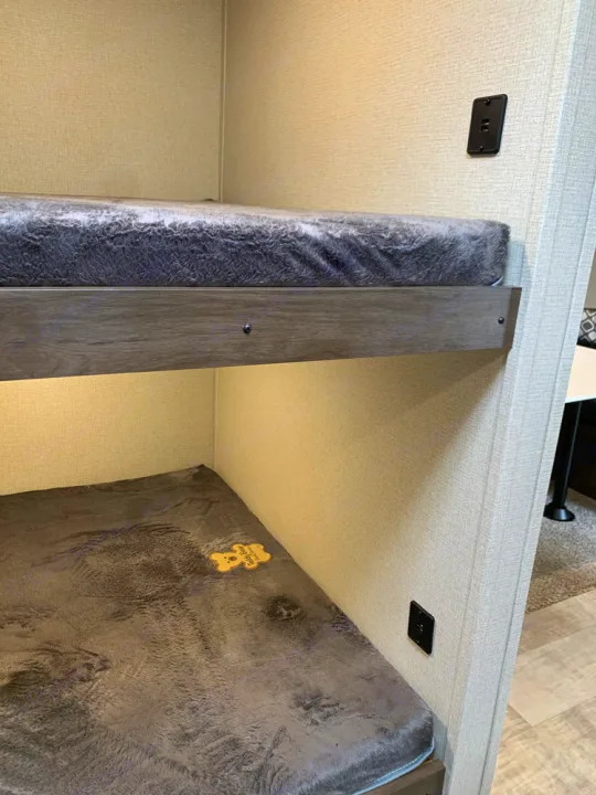 Cozy bunk beds in an RV rental, featuring soft gray mattresses, under-bunk lighting, and power outlets.. Prime Time Avenger 2021