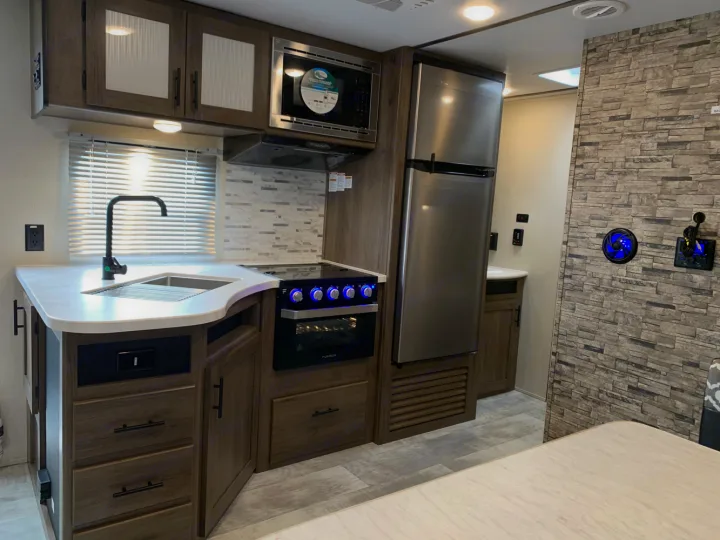 Modern RV rental kitchen with stainless steel appliances, sink, oven, and stylish backsplash.. Prime Time Avenger 2021