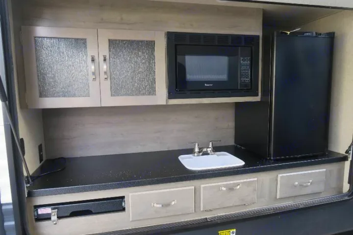An RV rental's outdoor kitchen features a microwave, mini-fridge, sink, and griddle/cooktop. Ideal for al fresco dining.. Palomino Puma 2018