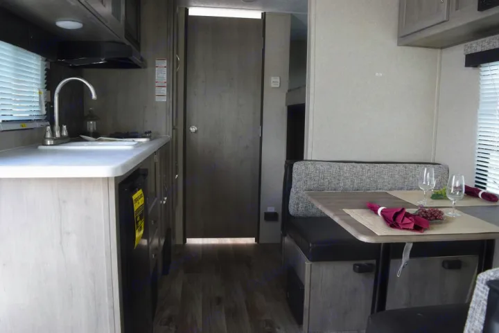 Bright RV rental interior: well-equipped kitchenette, light wood cabinetry, and a cozy dinette setup for travel comfort.. Forest River X-Lite 2020
