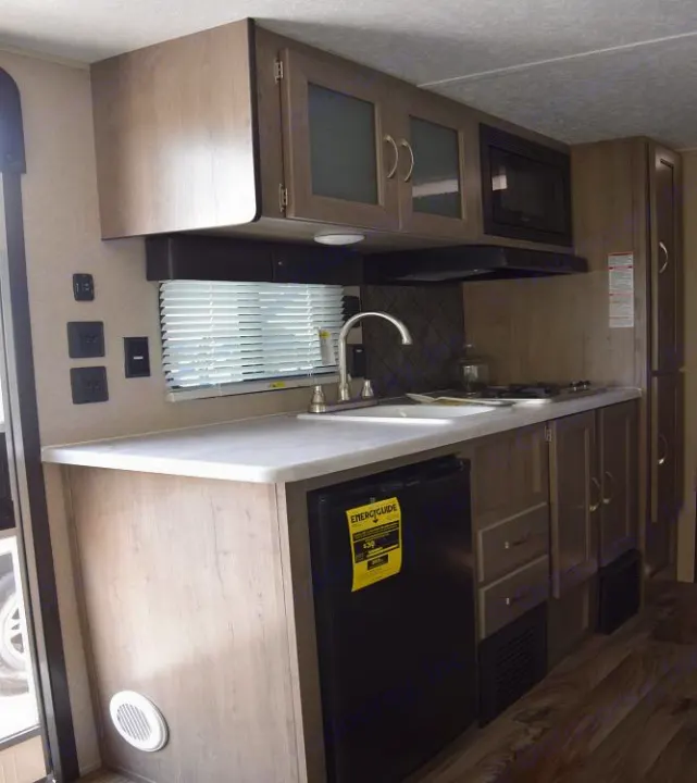 RV rental interior: a modern RV kitchenette featuring a sink, stovetop, microwave, and mini-fridge. Ideal for your next road trip.. Forest River X-Lite 2020