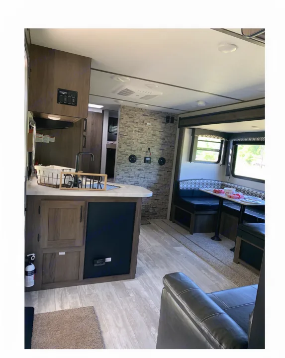 Explore this RV rental's spacious interior: kitchen, dining booth, and living area with armchair. Your comfortable home on wheels.. Prime Time Avenger 2021
