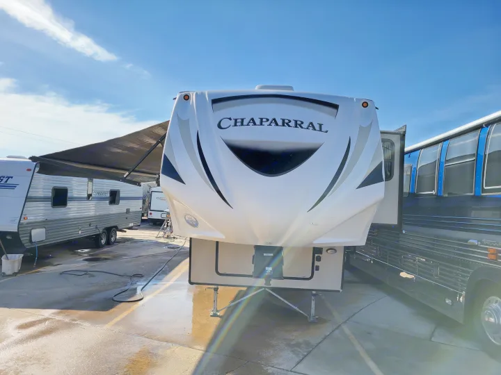 Front view of a Chaparral fifth-wheel RV at an outdoor lot. Other RVs and a bus are visible, hinting at rv rental or sales.. Forest River Chaparral 2017