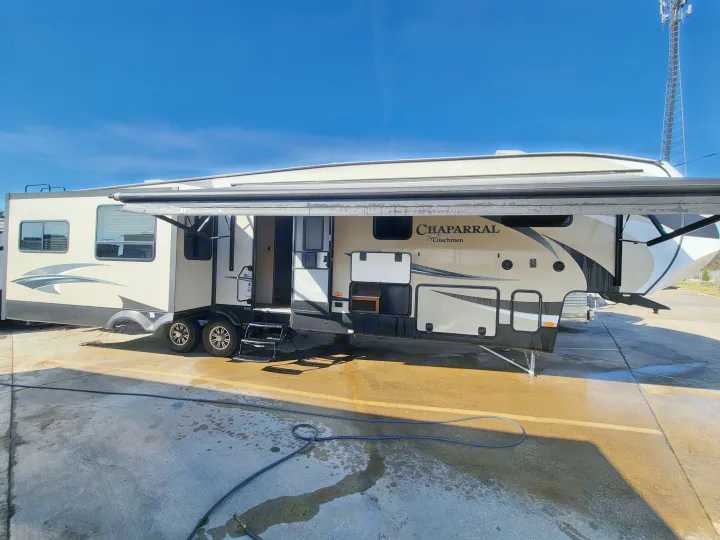 Spacious Chaparral Coachmen RV rental with awning extended, parked on a concrete lot under a clear blue sky.. Forest River Chaparral 2017