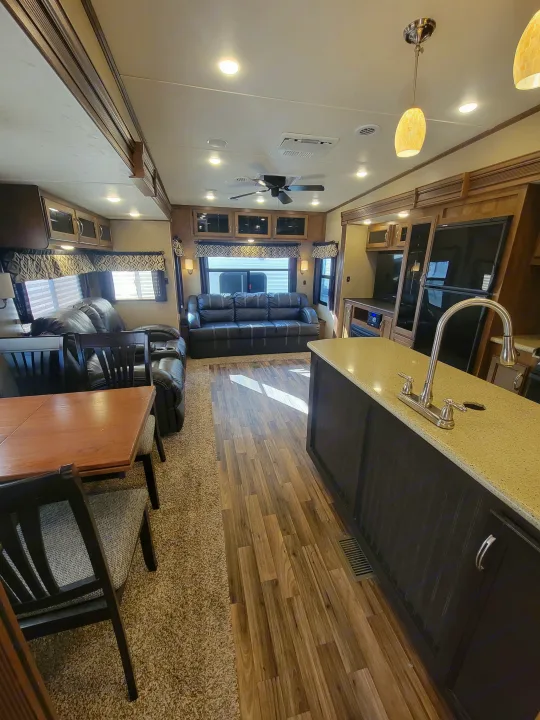 Spacious RV rental interior featuring a full kitchen island, comfortable living area with a sofa, and dining space.. Forest River Chaparral 2017