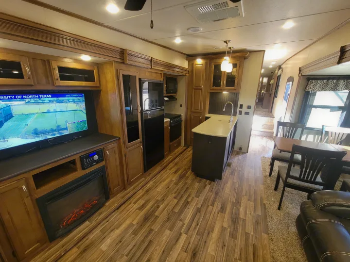 Modern RV rental interior showing a full kitchen, dining area, and living space with TV & fireplace.. Forest River Chaparral 2017