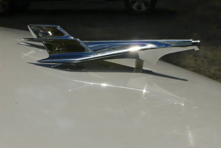 Sleek chrome hood ornament, common on a classic car or vintage RV rental, gleaming in the sun.. Ford E350 Box Van 2003