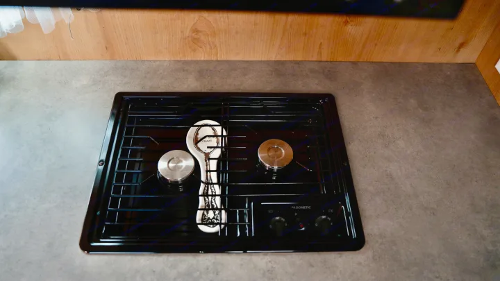 Inside an RV rental: a modern, black Dometic two-burner gas cooktop and gray counter, perfect for camp cooking.. Old School 818 2021