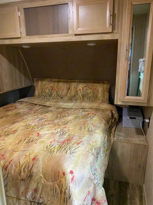 Cozy RV rental bedroom with floral bedding, overhead cabinets, and convenient charging station.. Forest River Coachmen Catalina Destination 2019