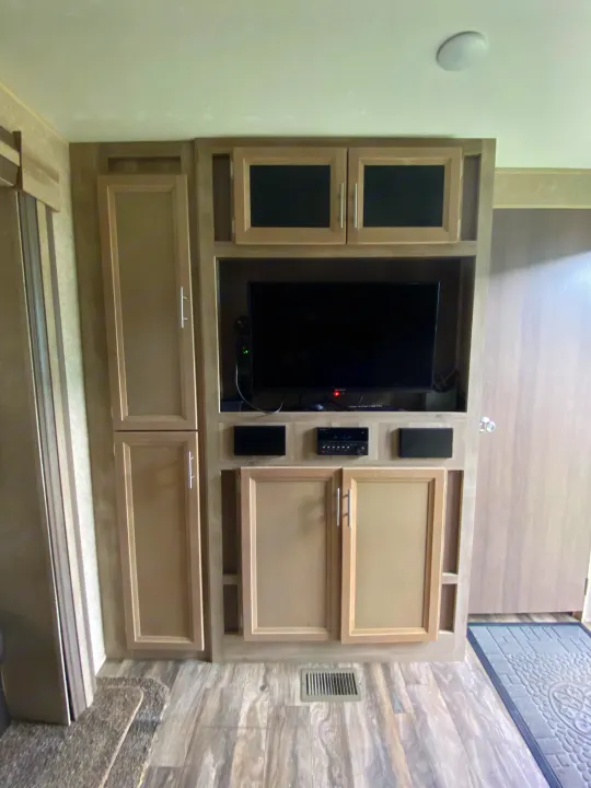 Modern RV rental interior featuring an entertainment center with TV, stereo, speakers, and ample storage cabinets.. Forest River Coachmen Catalina Destination 2019