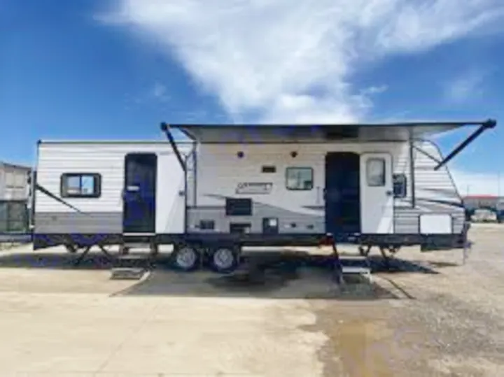 This spacious white & gray travel trailer, ideal for RV rental, features an extended awning, ready for outdoor adventures.. Coleman Lantern 300tq 2022
