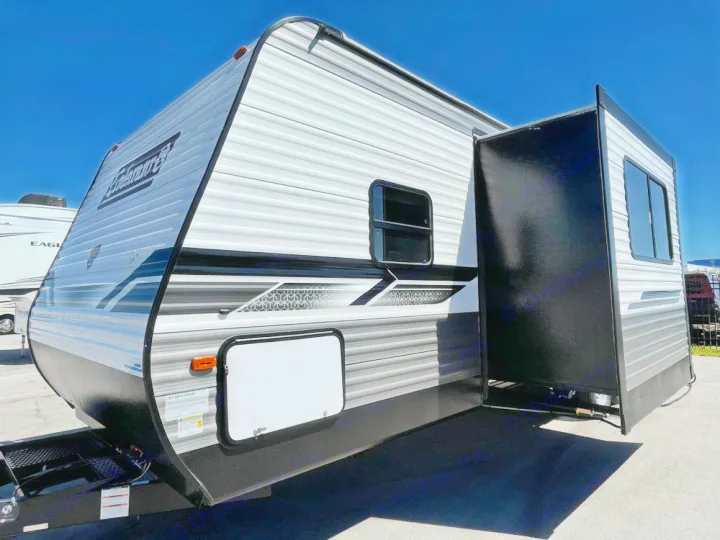 A modern Coleman travel trailer, ideal for an RV rental, shows its extended slide-out under a clear sky.. Coleman Lantern 300tq 2022