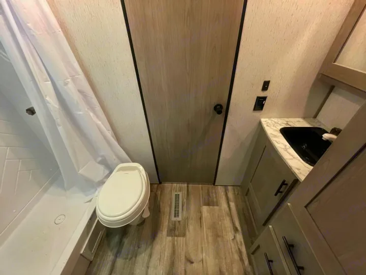 Compact RV rental bathroom featuring a shower, toilet, and vanity with a sink. Ideal for on-the-go comfort.. Coleman Lantern 300tq 2022
