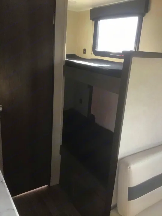 Compact RV rental interior featuring bunk beds and a bright window, ideal for road trips and family travel.. Coachmen Clipper 2020