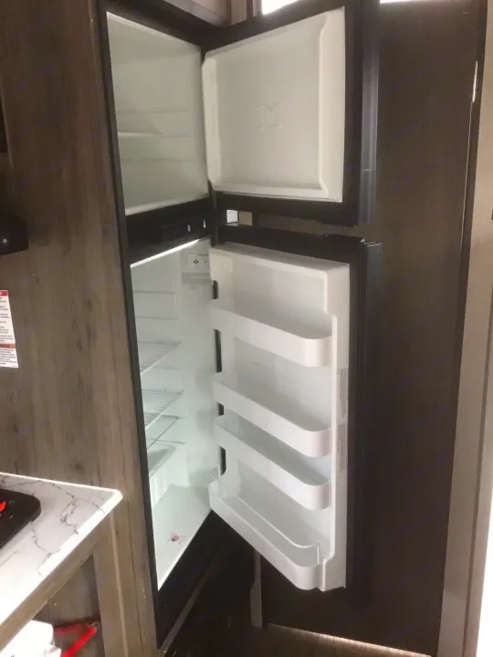 Explore your RV rental: This image shows an open compact refrigerator and freezer, essential kitchen appliances for your journey.. Coachmen Clipper 2020