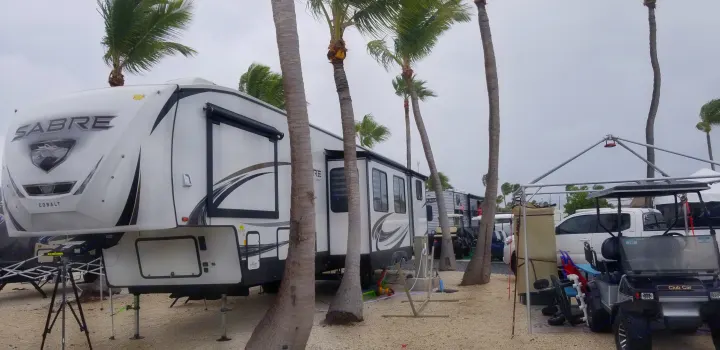 Sabre Cobalt fifth-wheel RV rental at a windy outdoor park with swaying palm trees & other vehicles.. Forest River Sabre 2021