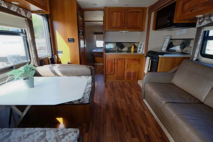 Explore this inviting RV rental interior: living area, full kitchen, and a peek into the bedroom, ideal for adventures.. Jayco Greyhawk 2016
