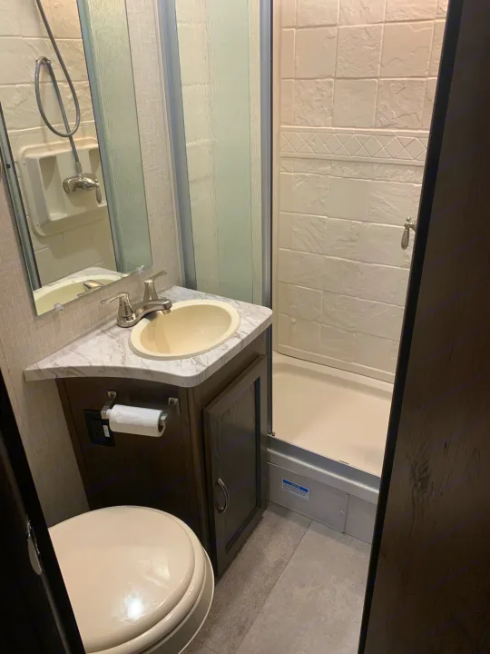 Inside an RV rental bathroom, featuring a compact shower, vanity sink, and toilet for travel convenience.. Forest River Coachmen Prism 2020