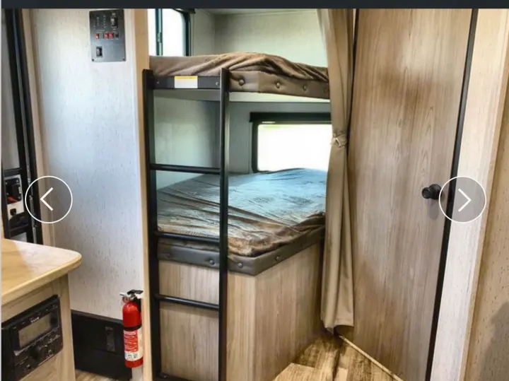 Inside an RV rental, two bunk beds, a control panel, and a red fire extinguisher are clearly visible.. Coleman Lantern 2022