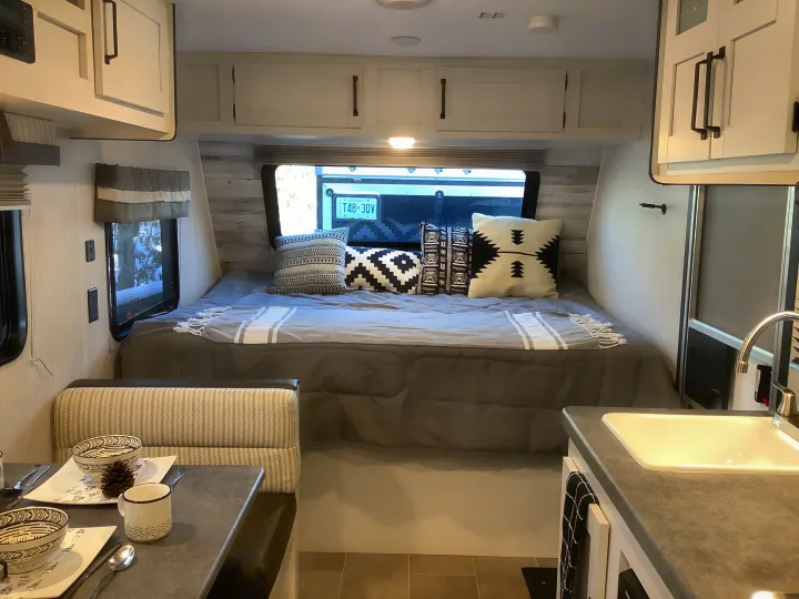 Ontario RV rental's cozy interior: bed, dining area, and kitchen with sink, ideal for your next trip.. Other Other 2021
