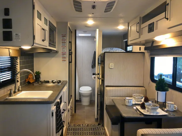 Modern RV rental interior: A bright, compact space with kitchen, dining area, and bathroom, featuring light tones and functional design.. Other Other 2021