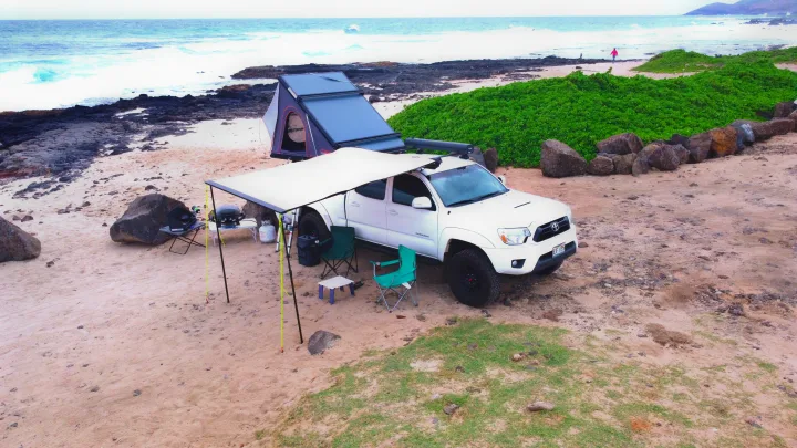 Beach overlanding with an RV rental truck, showcasing a rooftop tent, awning, and complete outdoor living setup.. Toyota Tacoma 2015