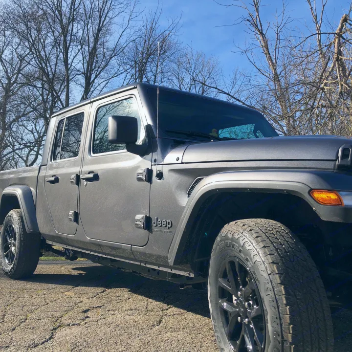 A grey Jeep Gladiator pickup truck, great for outdoor trips or an RV rental adventure, is parked under a clear blue sky.. Jeep Gladiator 2021