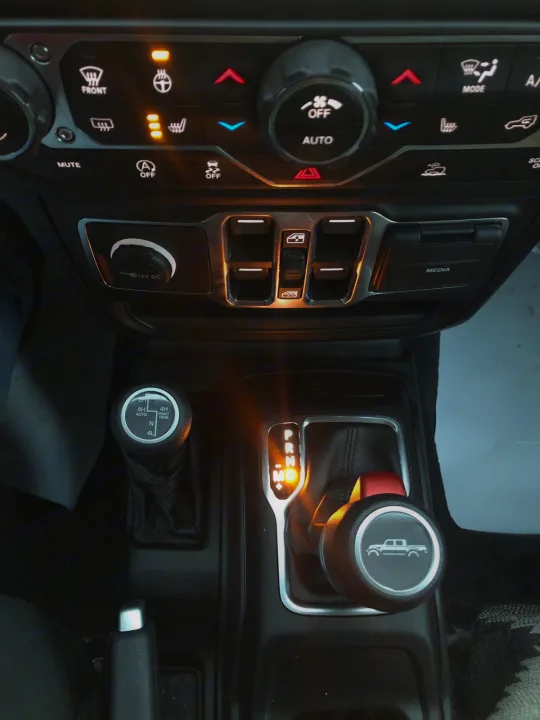 Vehicle interior, possibly an RV rental, showing illuminated dashboard controls and 4WD shifter.. Jeep Gladiator 2021