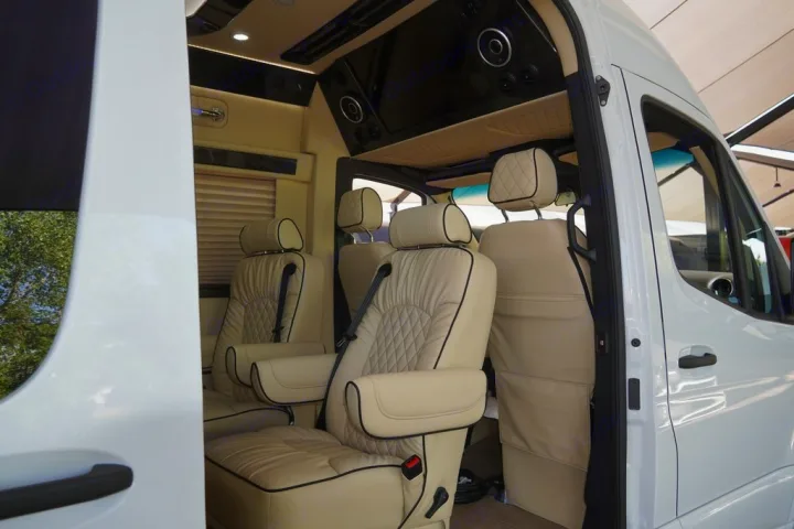 Luxurious RV rental interior with plush cream leather seats and entertainment system, perfect for comfortable travel.. Ultimate Toys Coach- Midwest Automotive Daycruiser D6 2022