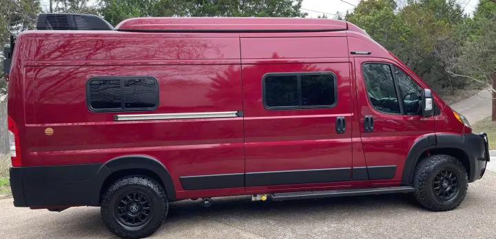 Striking red camper van, equipped with off-road tires and rooftop AC, ready for your next rv rental adventure.. Winnebago Solis 2021