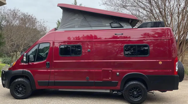 Stunning red pop-top camper van with rugged off-road tires, excellent for an RV rental adventure.. Winnebago Solis 2021