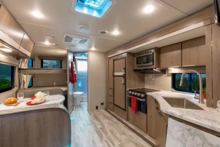 Spacious, modern RV rental interior featuring a full kitchen, dining area, bunk beds, and bathroom.. Grand Design Imagine XLS 2020