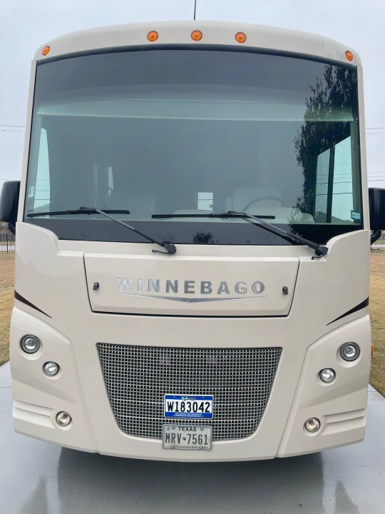 Front-facing view of a large beige Winnebago motorhome, featuring its grille, windshield, and Texas license plate. Consider for RV rental.. Winnebago Sightseer 2019