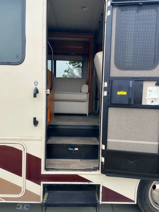Step inside this RV rental: The main door is open, revealing interior steps and a cozy sofa, ready for adventure.. Winnebago Sightseer 2019