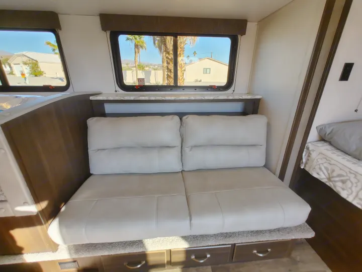 RV rental: Bright interior with convertible sofa seating, storage drawers, and scenic window views of palm trees.. Keystone RV Springdale 2020