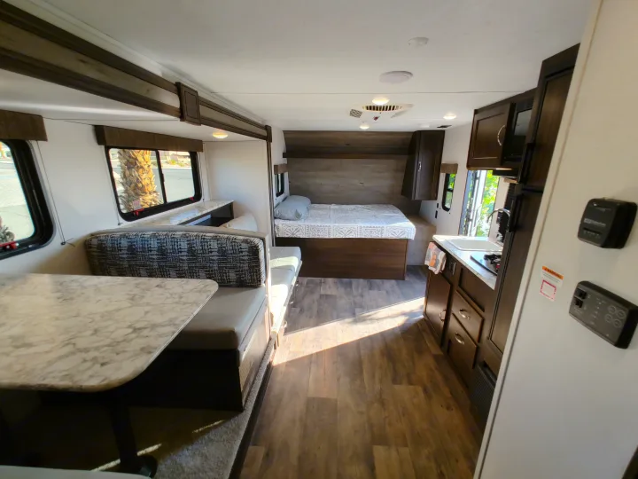 Bright RV rental interior showcasing a cozy dinette, comfortable bed, and functional kitchen. Ideal for adventure.. Keystone RV Springdale 2020