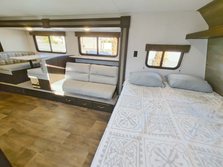 Spacious RV rental interior with bedroom, sofa, and dinette area, perfect for travel.. Keystone RV Springdale 2020