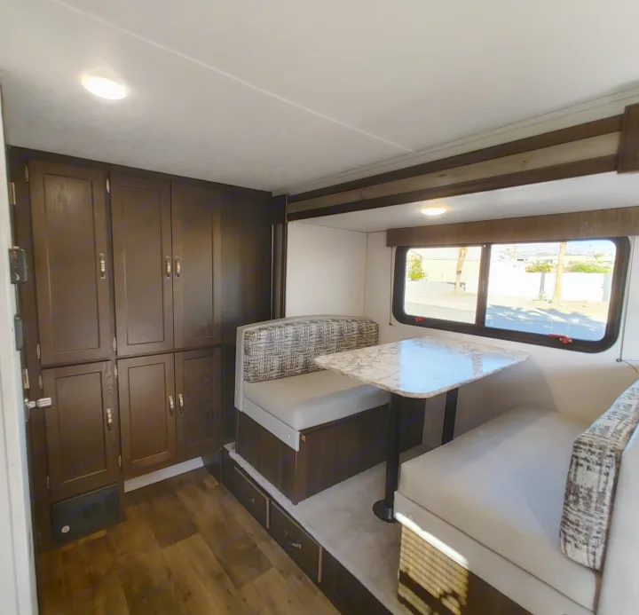 Spacious RV rental interior featuring a dinette with patterned cushions, a marble table, and ample storage cabinets.. Keystone RV Springdale 2020