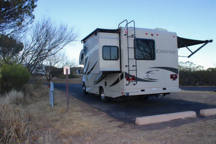 An **RV rental** beige motorhome with slide-out and awning extended, parked at a dry campsite. Ideal for road trip camping.. Other Other 2017