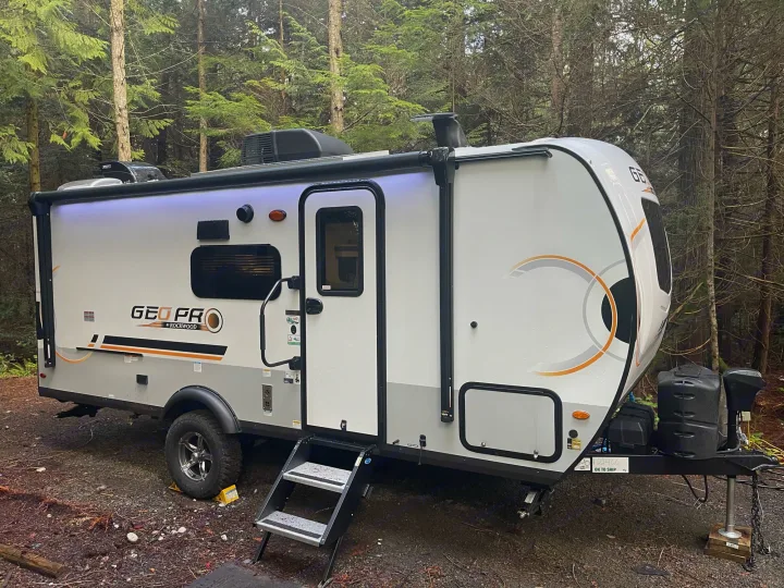 A modern travel trailer, ideal for an RV rental, is parked in a serene forest setting, ready for your camping adventure.. Forest River Other 2022