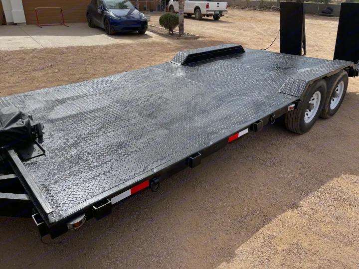 Heavy-duty black diamond plate car hauler trailer on a gravel lot. Ideal for RV rental vehicle transport.. Big Tex 20" Flatbed 2014