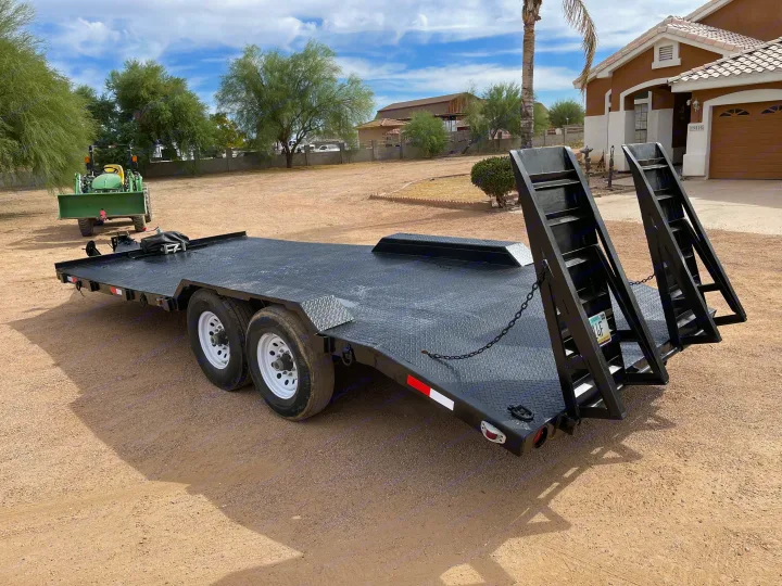 Black utility trailer with ramps on a dirt lot. Ideal for equipment hauling, possibly for an RV rental adventure.. Big Tex 20" Flatbed 2014