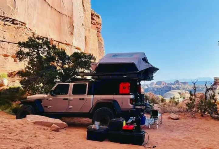 Jeep Gladiator with rooftop tent deployed, a unique RV rental for overlanding. Camping in a vast red rock canyon.. Jeep Gladiator 2020